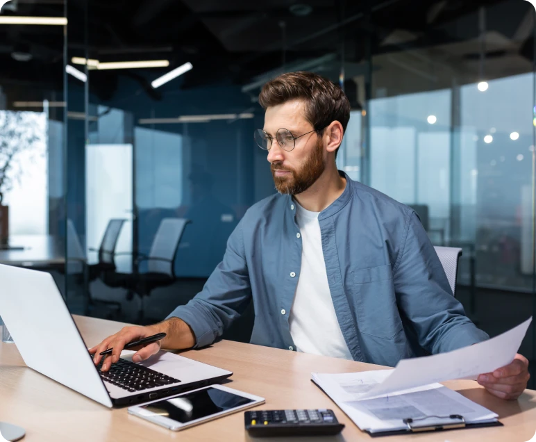 Professional reviewing paperwork on computer